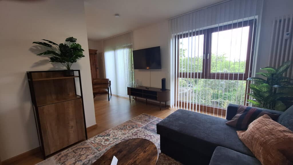 Wohnbereich mit Sofa und großem Fenster im Ferienappartement Typ A
